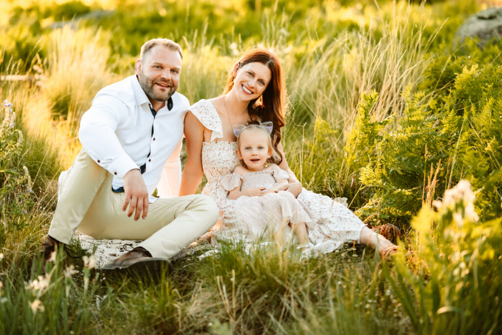 Family sitting in grass in white and cream clothes smiling in flagstaff by annie bee photography.