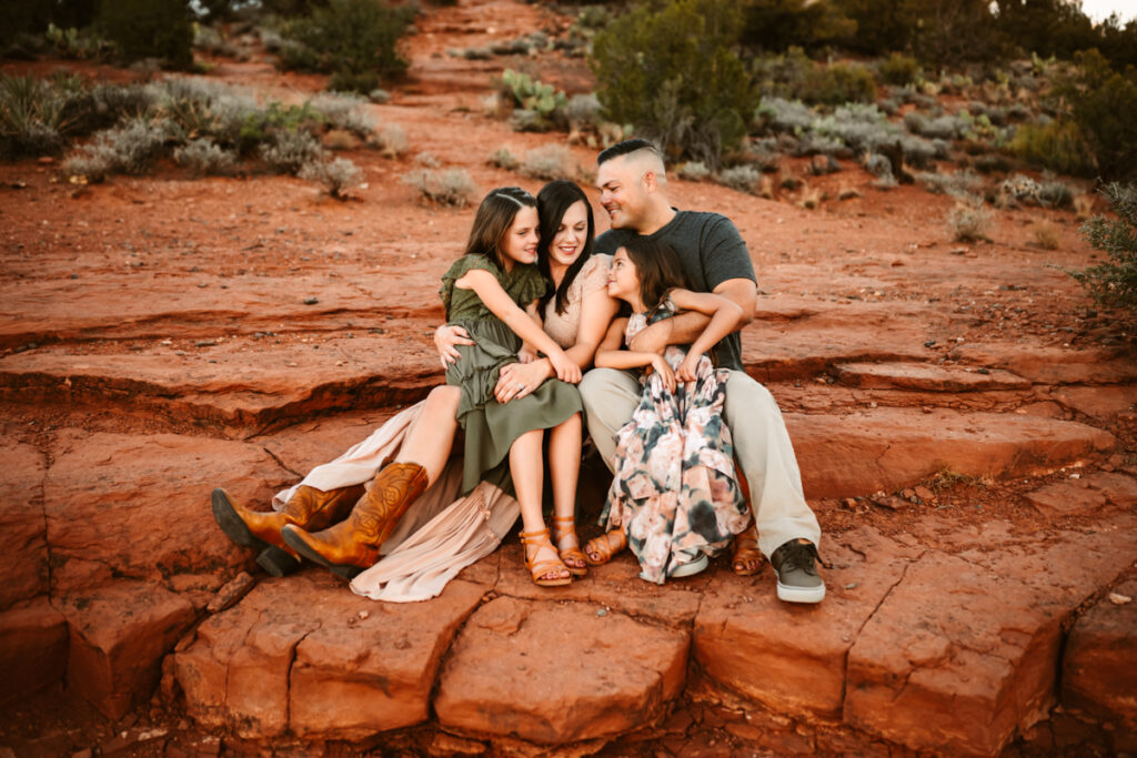 Family sitting on the red rocks of secret slick rock in sedona by annie bee photography.