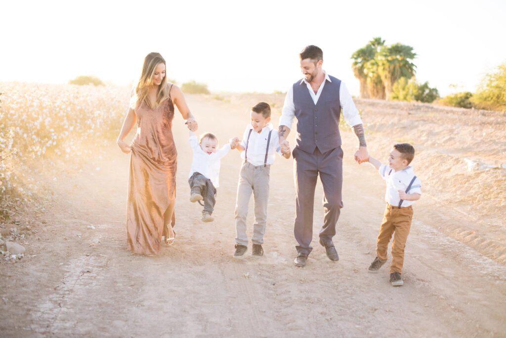 A Flagstaff family photographer captures a dressed up family walking through cotton fields in layered outfits.