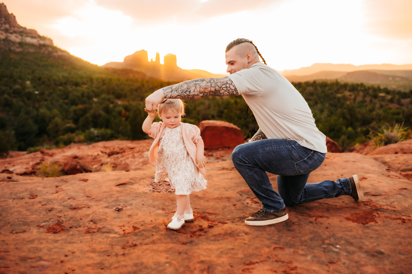 Dad twirling his daughter at Bell Rock in Sedona wearing stylized outfits.