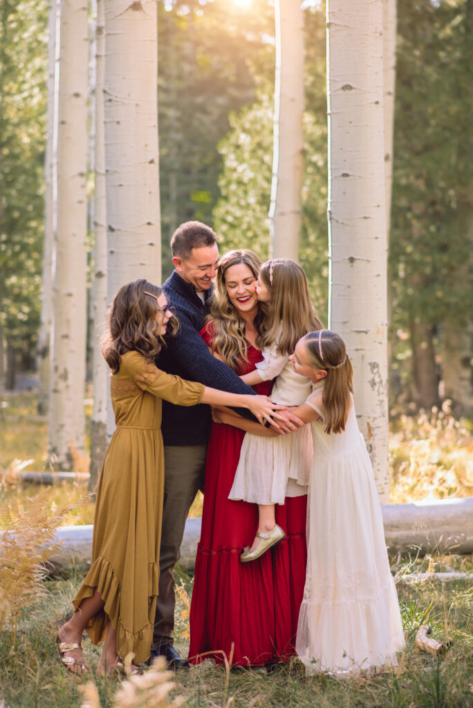 A family snuggling in the aspen trees in Joyfolie maxi dresses in Flagstaff.