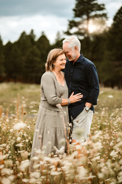 Grandparents snuggling for family portraits in a field of wildflowers in Flagstaff, Arizona during summer monsoons.