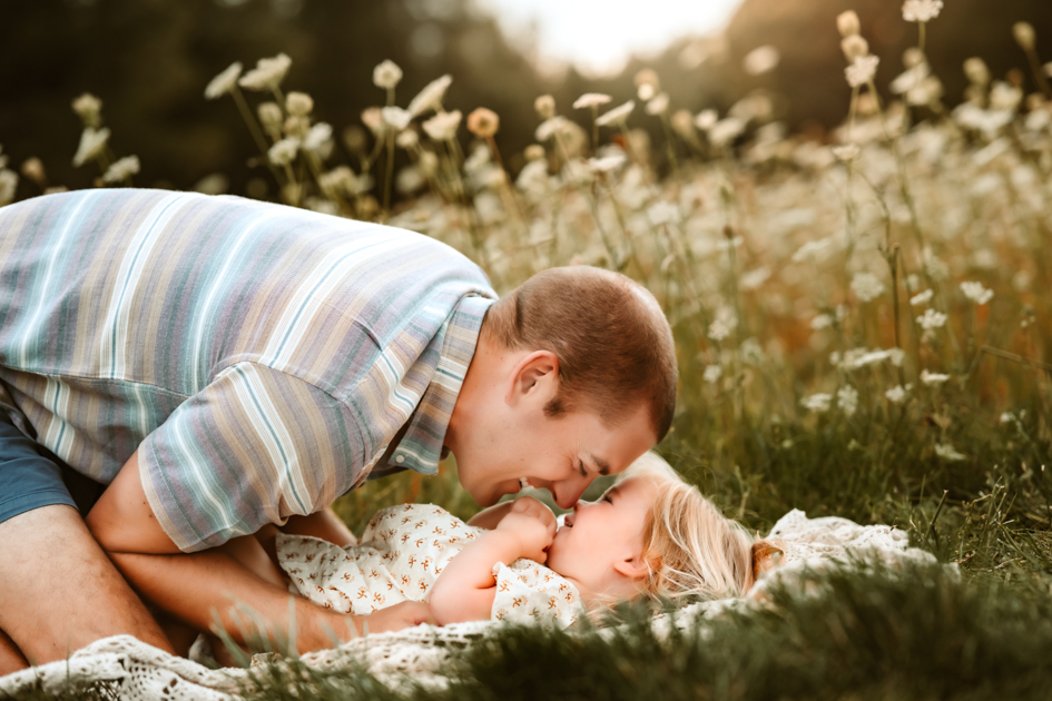 Dad and daughter laughing on a blanket in a field of wildflowers at Forest Highlands in Flagstaff, Arizona.