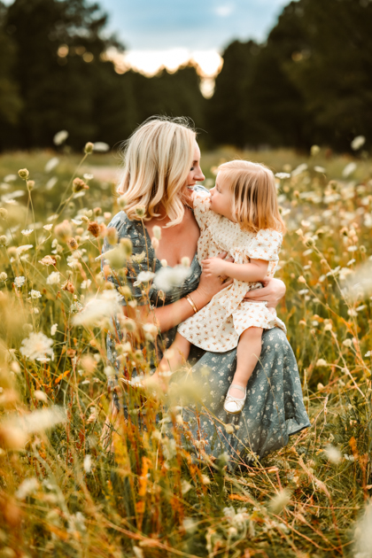 Mother and daughter snuggling in a field of wildflowers at Forest Highlands golf club in Flagstaff, Arizona.