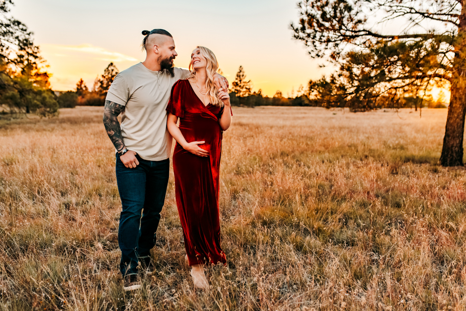 Maternity session of a husband and wife walking in a field at Buffalo Park in Flagstaff, Arizona.