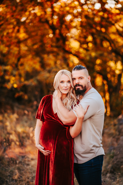 Pregnant mom holding her belly in a velvet dress at Buffalo Park in Flagstaff.