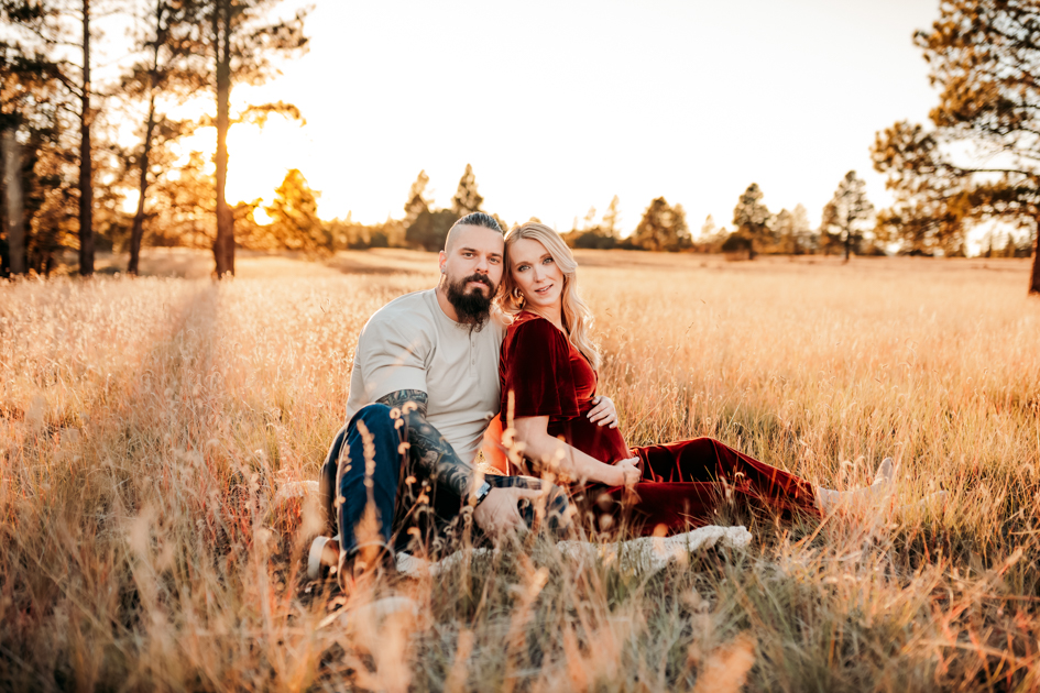 Couple expecting their first child posing for a portrait in a field at Buffalo Park in Flagstaff.