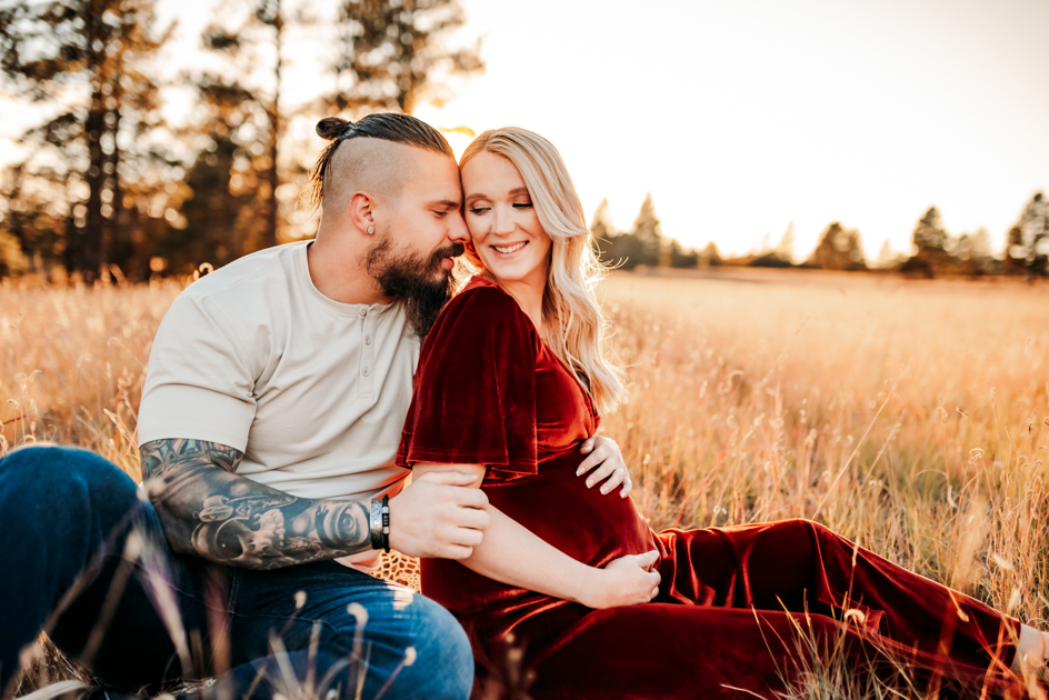 Pregnant woman laughing as her husband whispers in her ear at Buffalo Park in Flagstaff, Arizona.