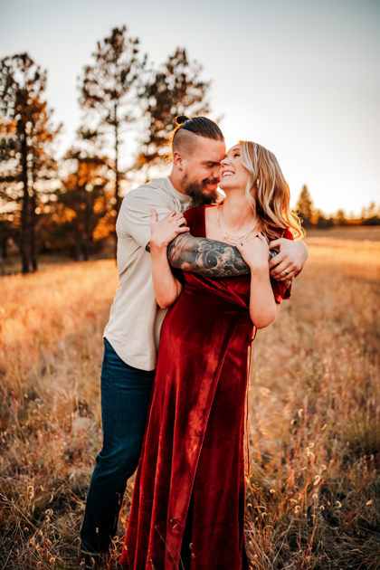 Expecting parents kissing in a field at Buffalo Park in Flagstaff during fall.