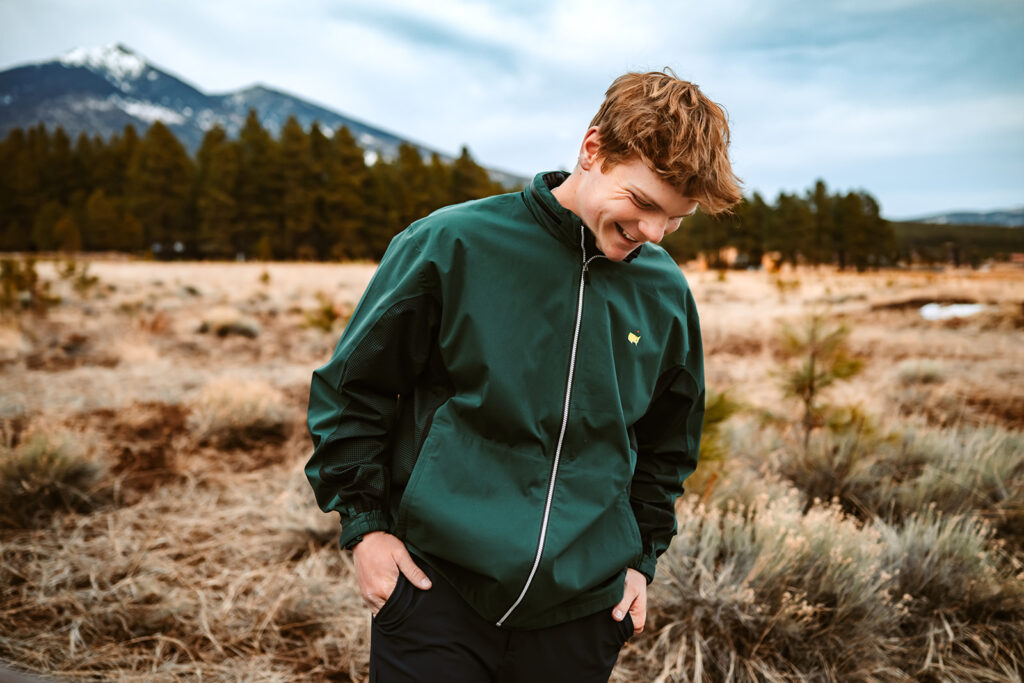 Graduate senior golfer laughing in front of Mount Humpreys in Flagstaff.