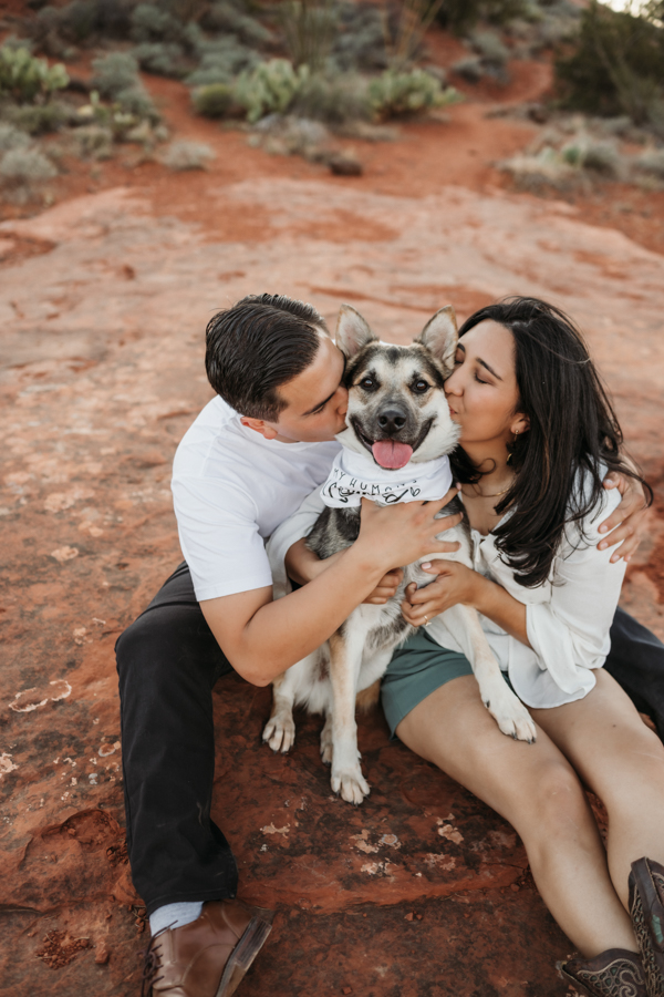 Couple kissing their dog with a bandana that says My Humans Are Getting Married in Sedona by Annie Bee Photography.