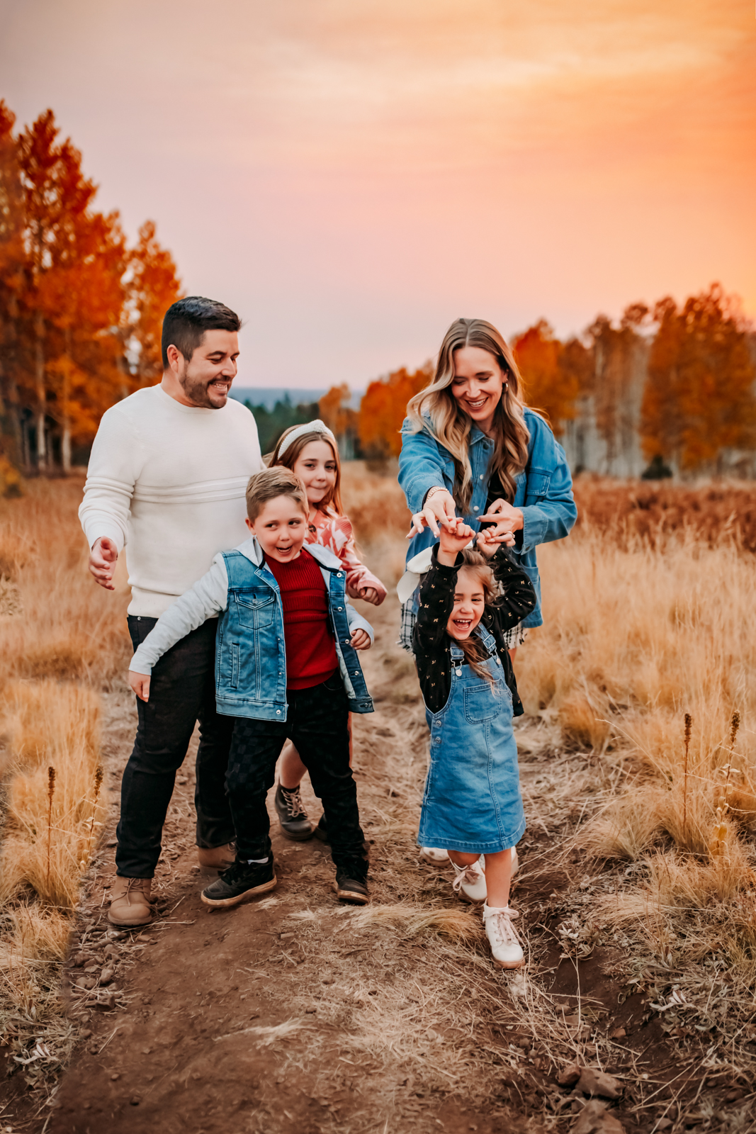 Flagstaff family photographers with children dancing for fall photos in the aspen trees of Flagstaff dressed in denim at their arizona mini sessions.