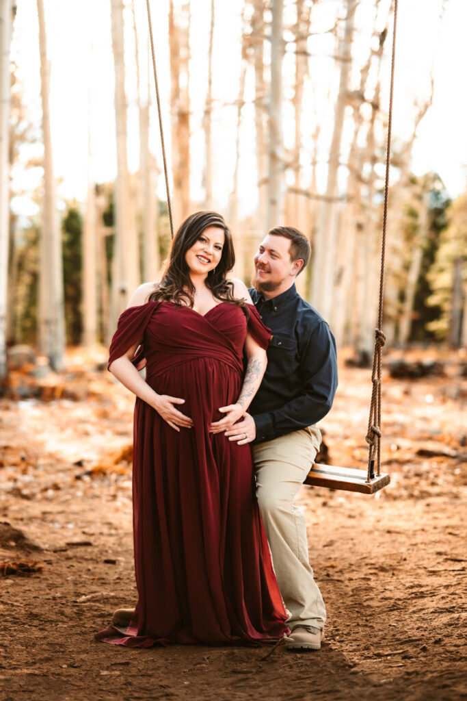 Aspen corner on Snowbowl of mom in a red dress with husband on a swing