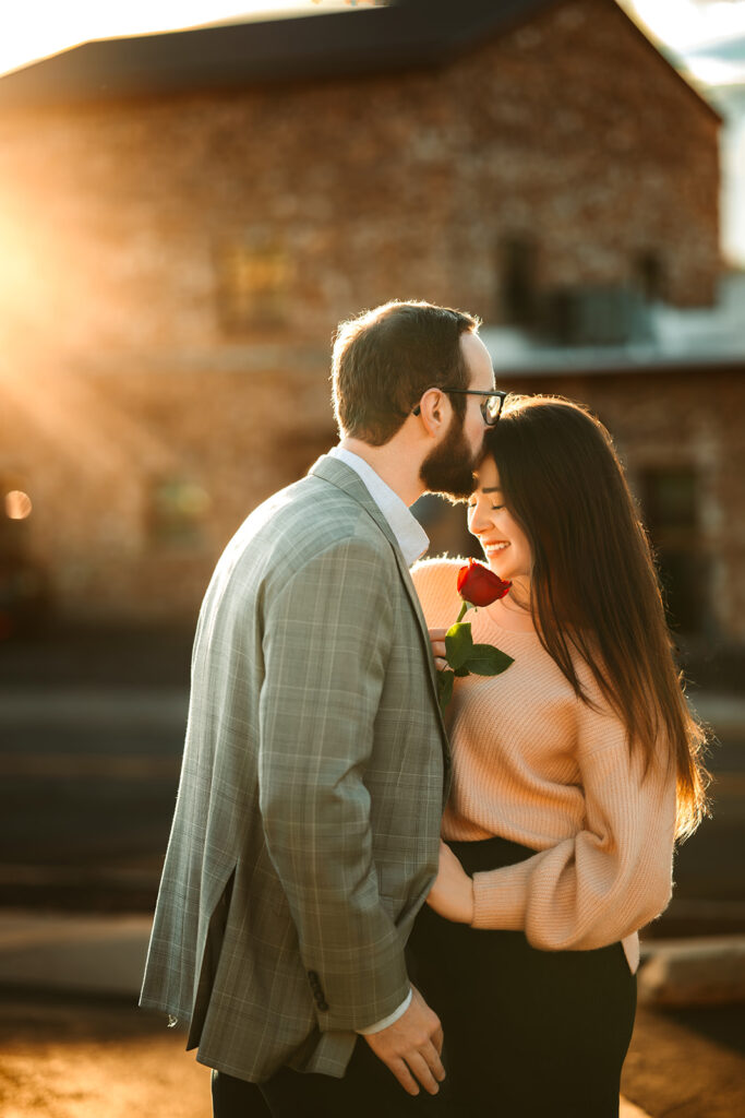 Engaged man kissing his fiancés forehead in downtown flagstaff, Arizona.