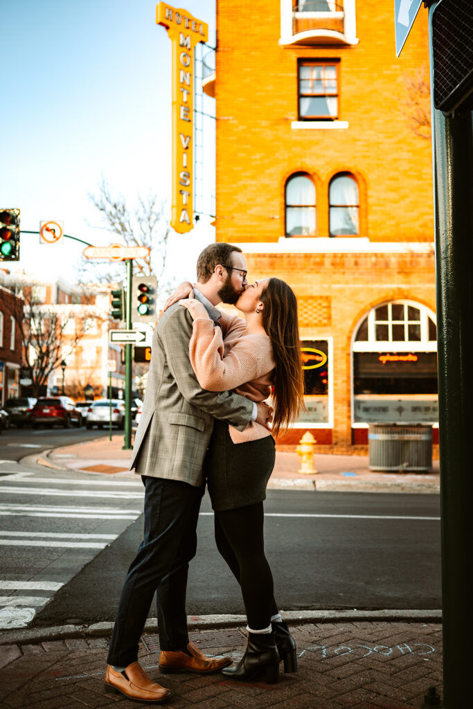 Couple kissing on the street in downtown Flagstaff, AZ with the Hotel Monte Vista sign in the background.