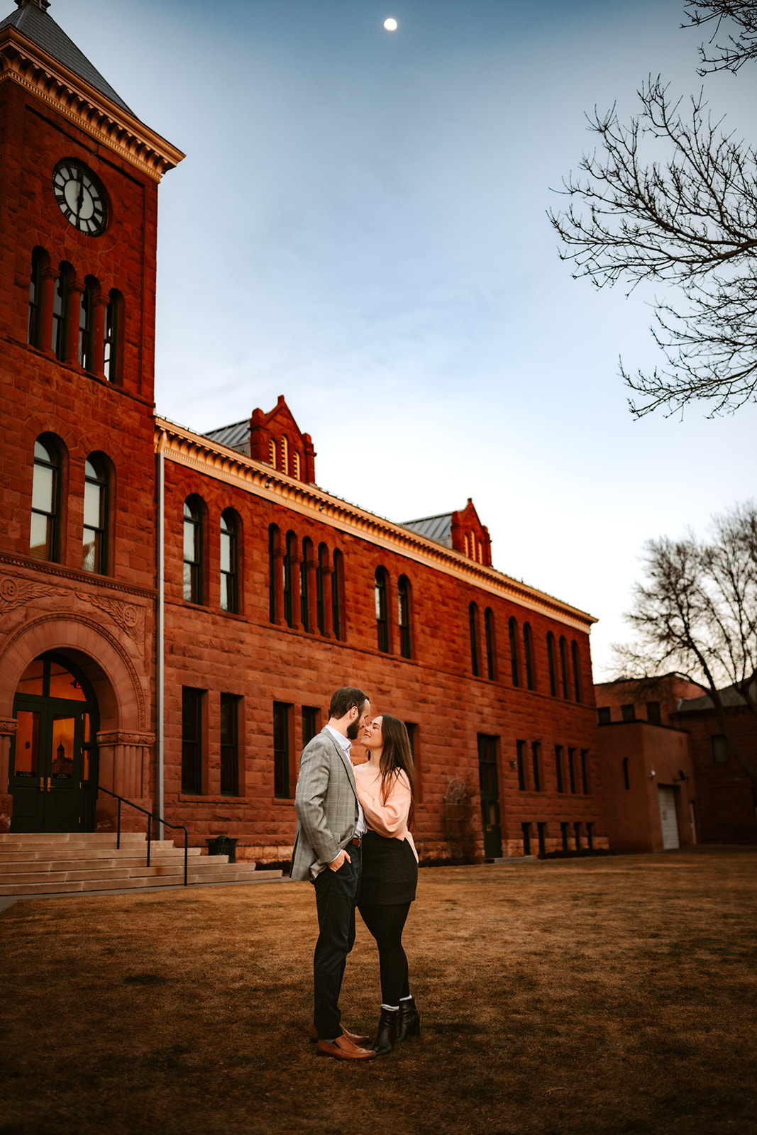 Newly engaged couple hugging in front of the courthouse in downtown flagstaff.