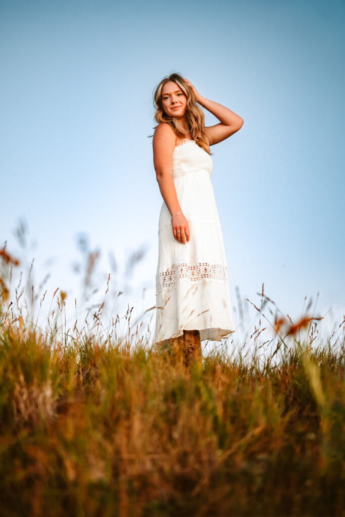 Arizona senior graduate on top of a hill in a white dress at Snowbowl.