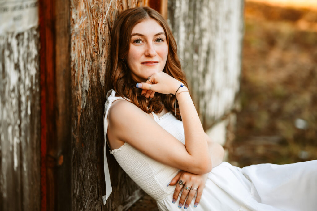Graduate sitting on stairs of an old cabin in flagstaff by annie bee photography at the best Flagstaff photo locations.