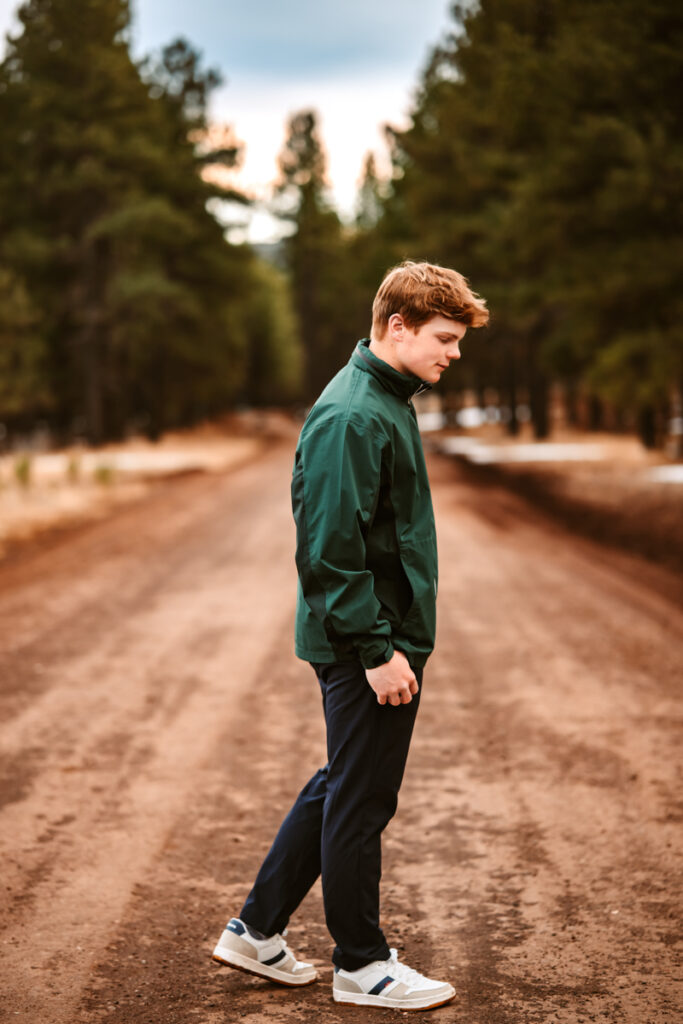 Senior boy walking on a road in flagstaff in his soccer uniform by annie bee photography at the best Flagstaff photo locations.
