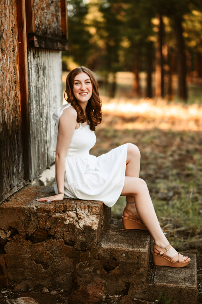 Senior girl smiling on a staircase in flagstaff by annie bee photography in a white dress.