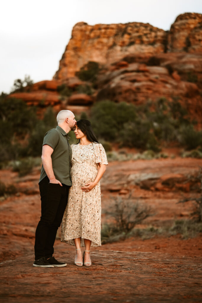 Husband kissing wife with the Sedona red rocks in the background.