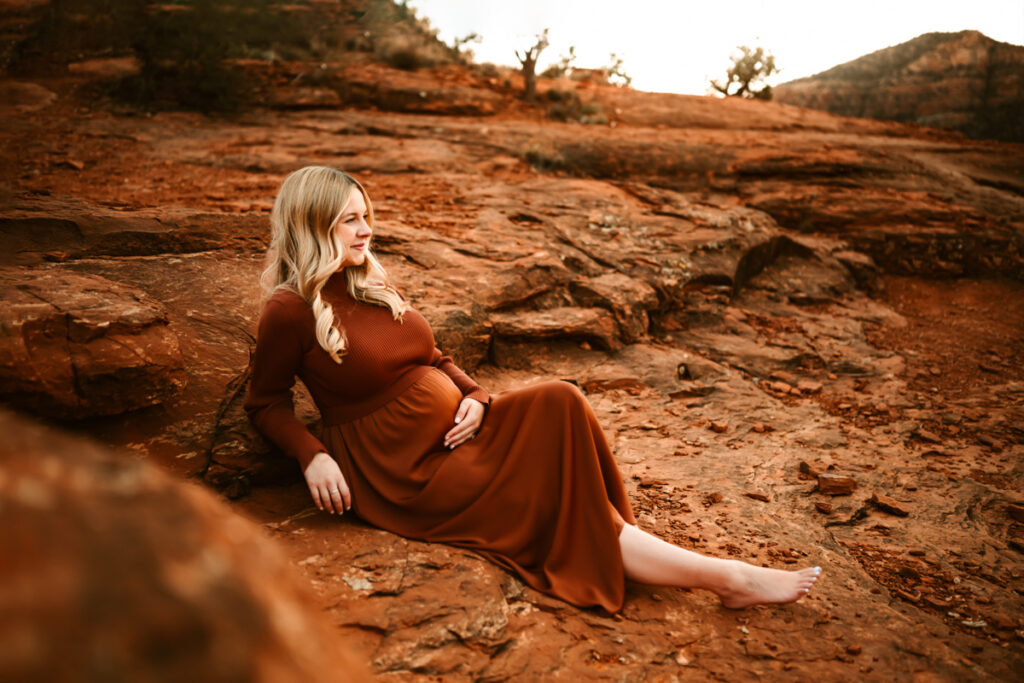Expecting mom laying on the red rocks of sedona at bell rock.
