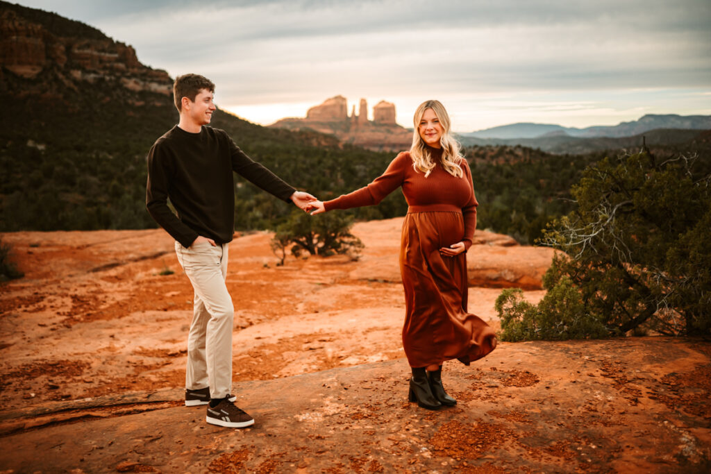 Expecting couple holding hands at bell rock in sedona.