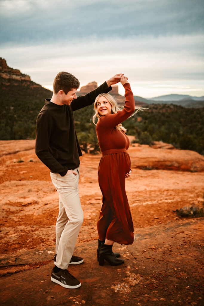 Husband and wife expecting dancing in the red rocks of sedona with cathedral rock.
