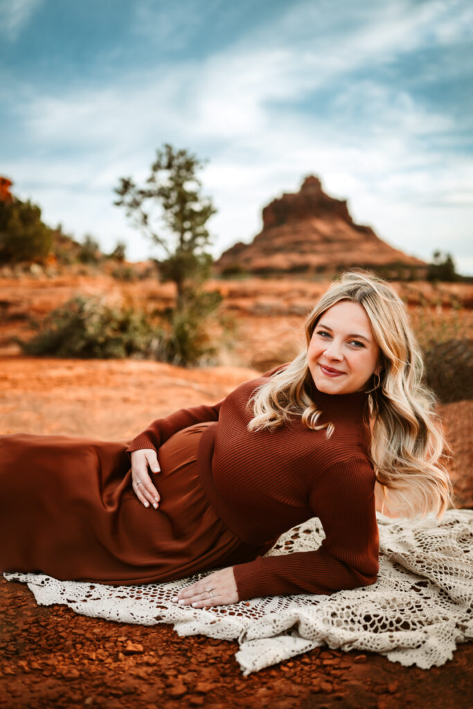 Mom in a maternity dress holding belly with bell rock in the background.