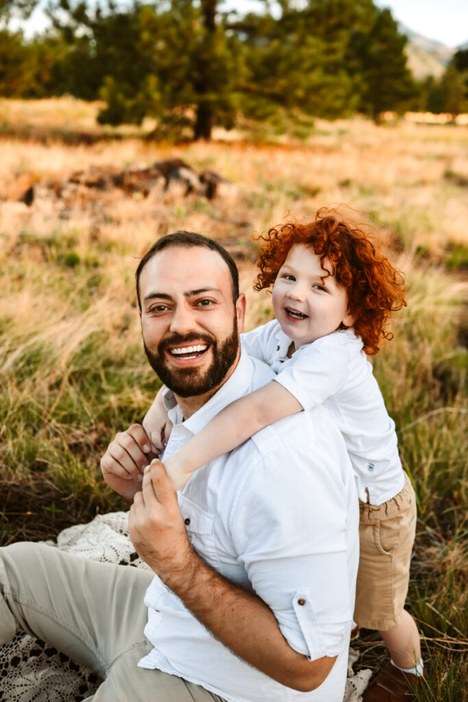 Father and son laughing sitting in a field in flagstaff by annie bee photography.