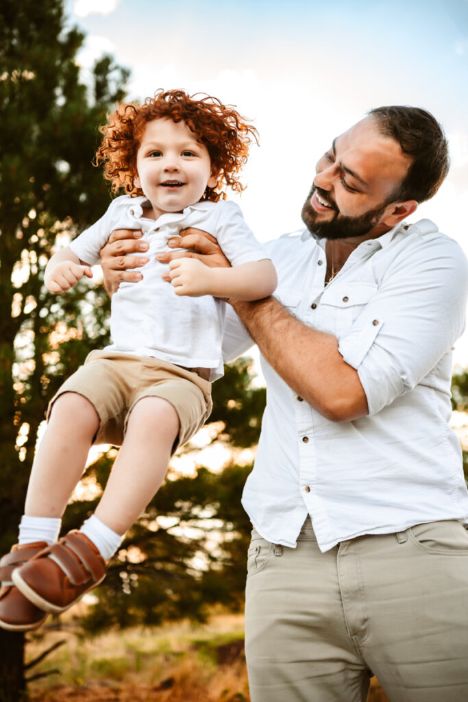 Father throwing up son in the park by annie bee photography.