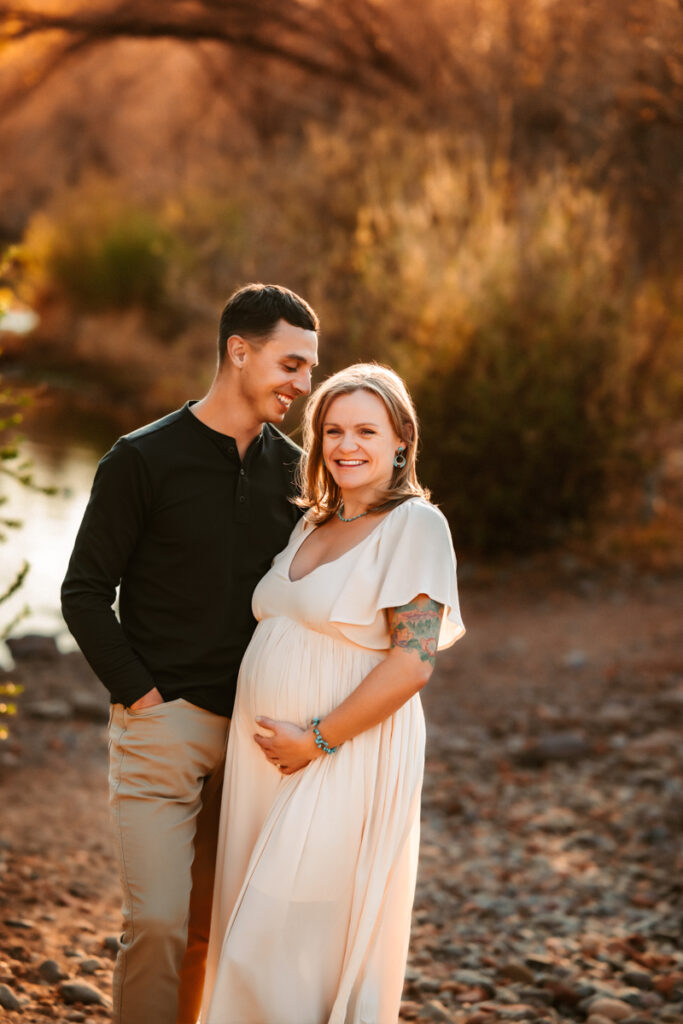Expecting couple at the creek laughing in Sedona.