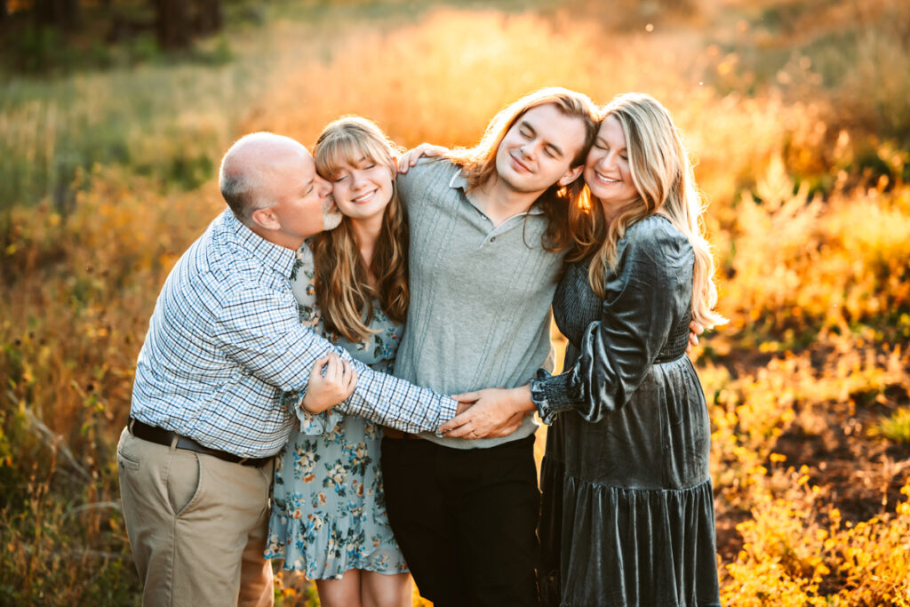 Mom and dad hugging their two kids in a field at kachina wetlands at the best Flagstaff photo locations