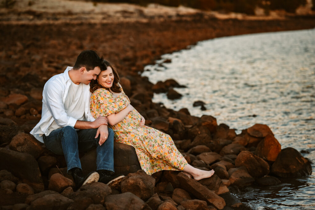 Expecting couple laying on the beach of Lake Mary in Flagstaff.