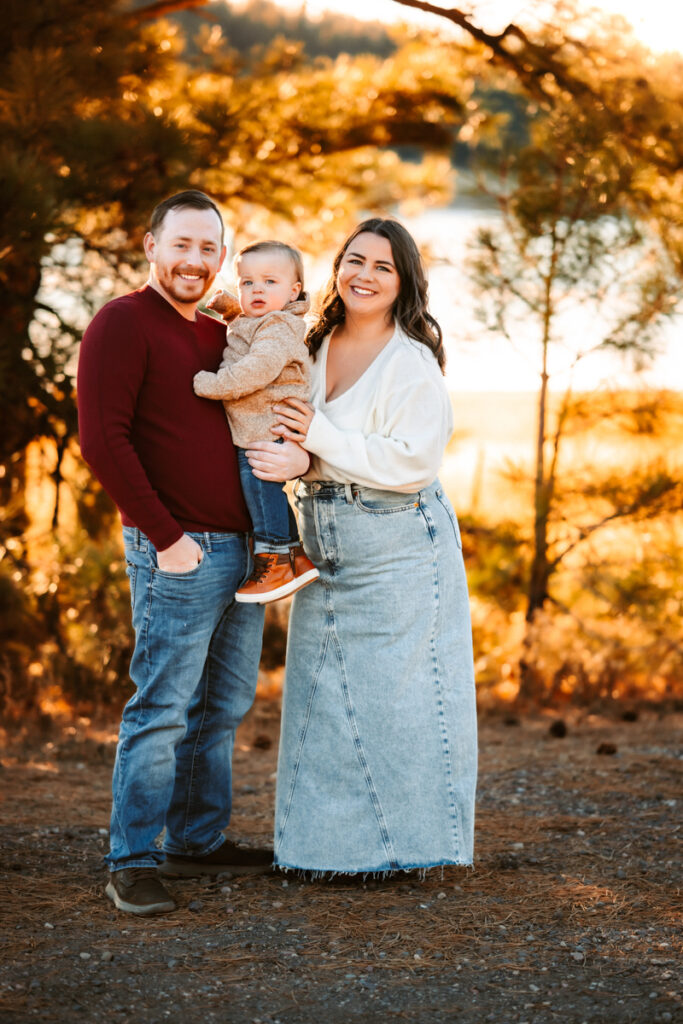 Mother and father smiling with their toddler in front of lake mary in flagstaff.