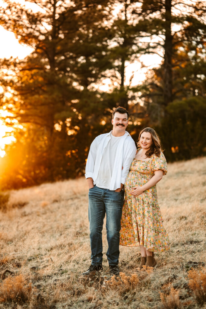 Husband and wife expecting their first baby holding hands in the forest of Flagstaff.