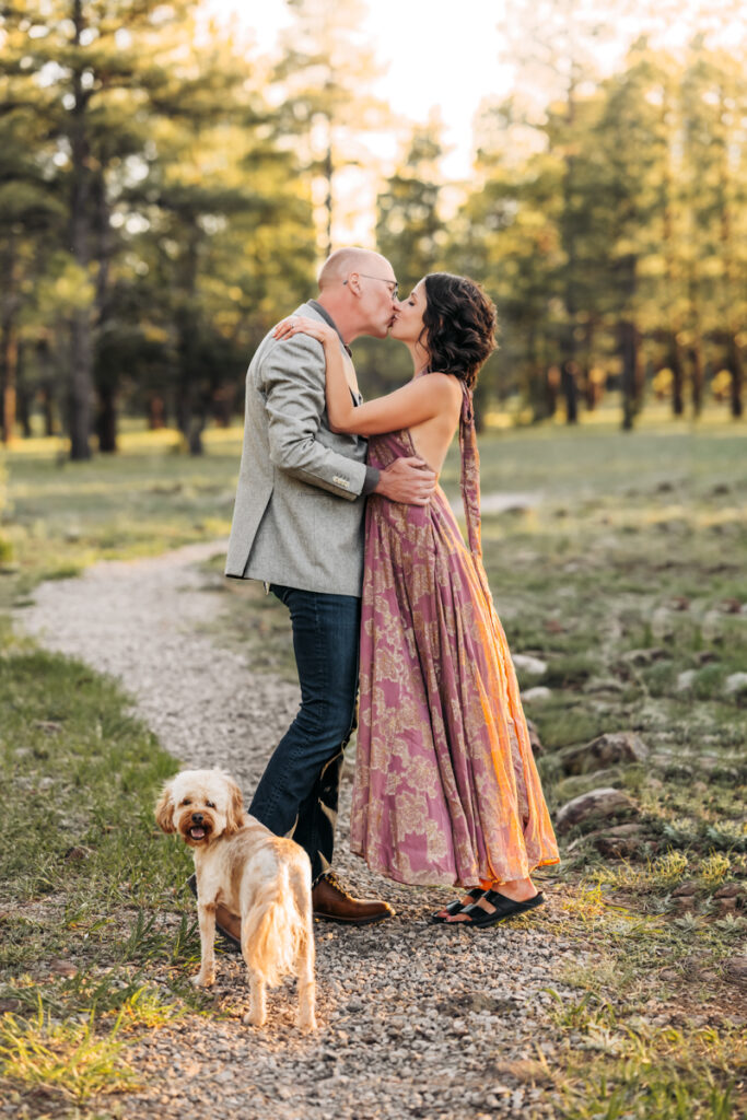 Husband and wife kissing on the arizona trail with their dog by annie bee photography at the best Flagstaff photo locations.