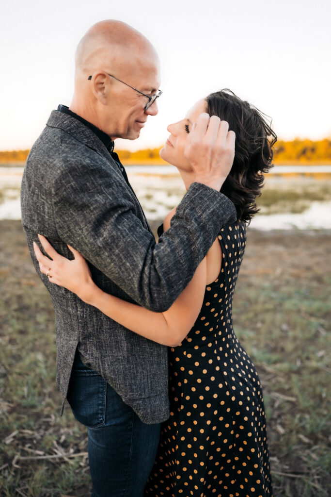 Husband and wife hugging in front of a lake in flagstaff by annie bee photography.
