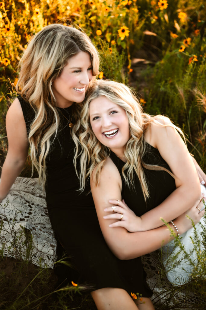 Mother daughter dressed in black laughing in a field of wildflowers in flagstaff by annie bee photography at the best Flagstaff photo locations.