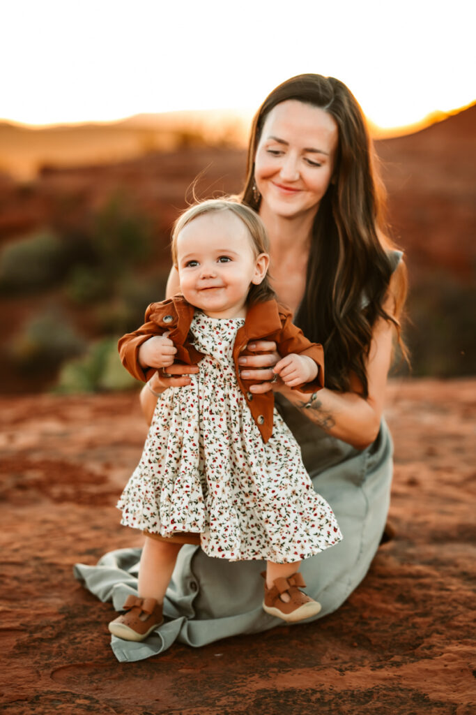 Mom holding her toddler girl in the red rocks of secret slick rock.