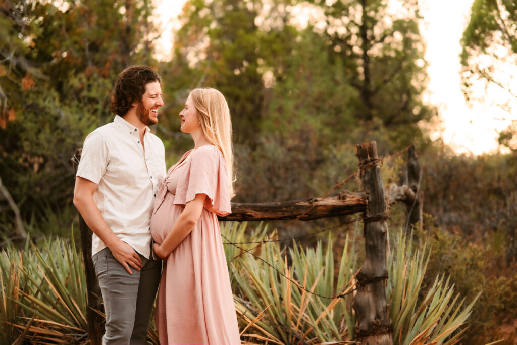 Maternity session of couple looking at each other in Sedona with cactus.